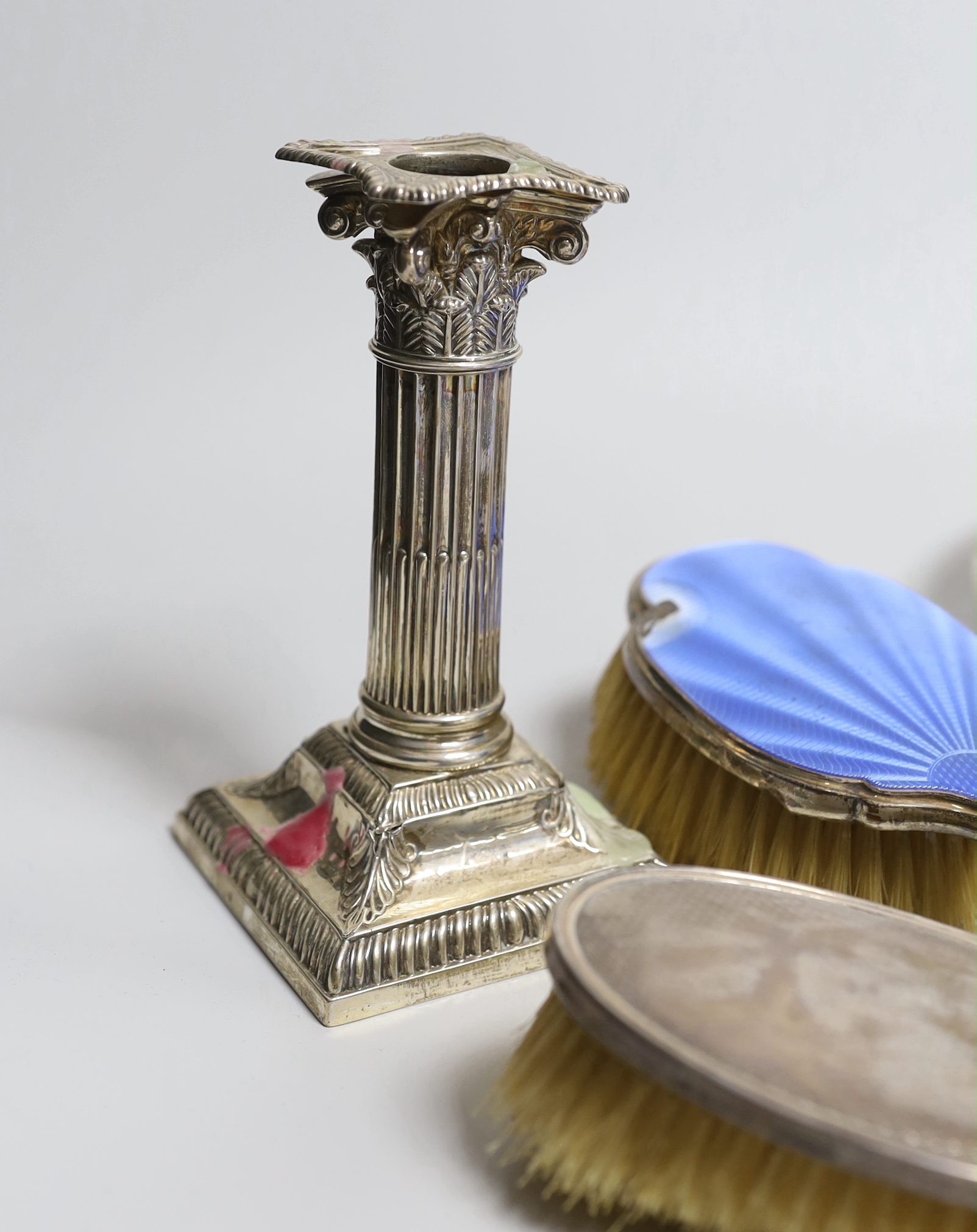 A pair of late Victorian silver corinthian column candlesticks, Thomas Bradbury & Sons, London, 1894, height 15.4cm (a.f.) a George V silver and enamelled six piece dressing table set (a.f.), together with a silver mount